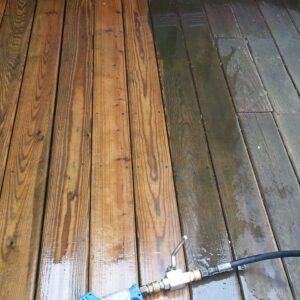 Closeup photo of a brown patio deck being soft washed and showing before and after