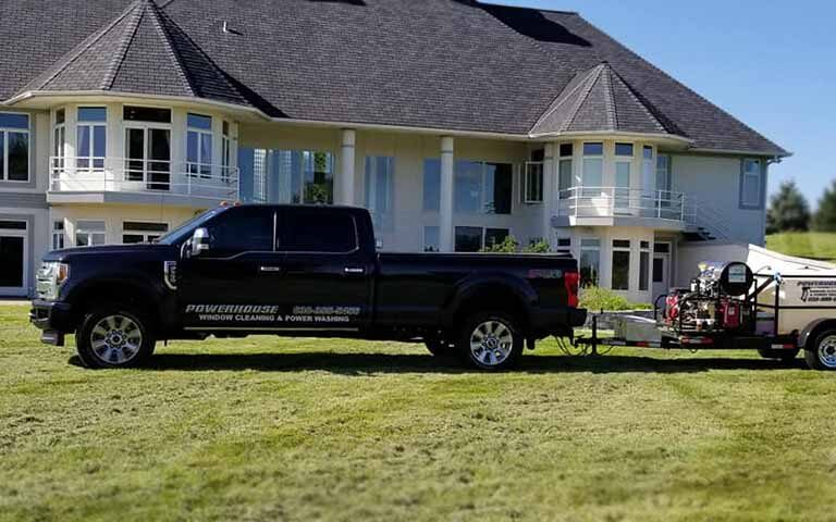 Photo of Powerhouse Pete's truck and power washing equipment on a grass lawn in front of a large house