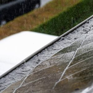 Photo of a clogged and overflowing gutter from the top-side while raining during a storm