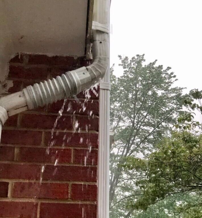 Photo of a downspout rain gutter leaking water that needs repair
